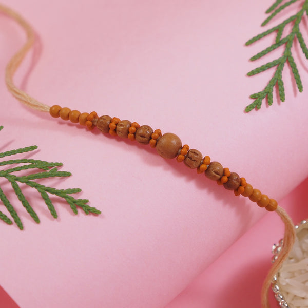 DELICATE PEARL WOOD RAKHI WITH ROLI CHAWAL & RAKSHABANDHAN CARD